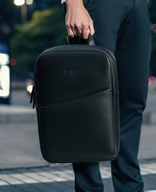 Mochila Slim Couro Preta e NYC Modelo Segurando Alca